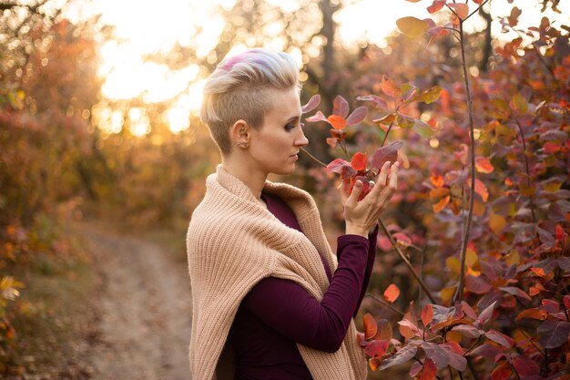 Stilvolle Hipster-Frau lächelt und spielt mit Herbstlaub im Park Herbstfrau fällt