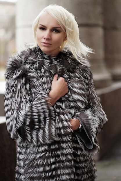 Stilvolle junge blonde Frau im Winterlook winter