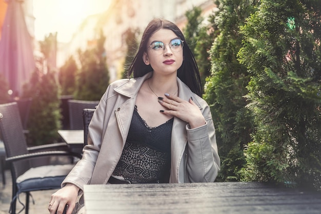 Stilvolle junge Frau, die an einem leeren Tisch sitzt und auf ihre Kaffeepause wartet