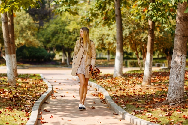 Stilvolle junge Frau, die in den herbstlichen Park geht