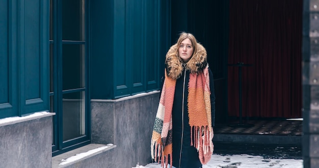 Stilvolle junge Frau in einer Jacke und mit einem Schal auf einem Winterspaziergang