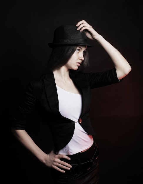 Stilvolle junge Frau mit schwarzem Hut, die für die Kamera posiert