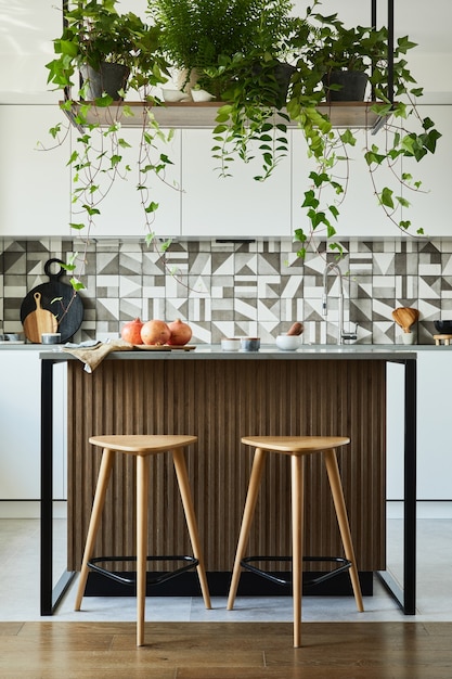 Stilvolle Kücheneinrichtung mit Essbereich. Arbeitsbereich mit Küchenzubehör im Hintergrund. Kreative Wände. Minimalistischer Stil ein Pflanzenliebeskonzept.
