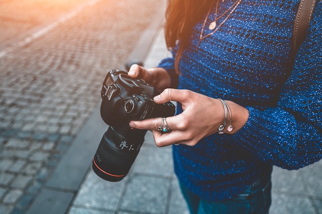 Stilvolle lässige reisende Fotograffrau, die Bilder mit digitaler DSLR-Kamera und Spiegelreflexobjektiv beim Gehen durch europäische Stadt macht