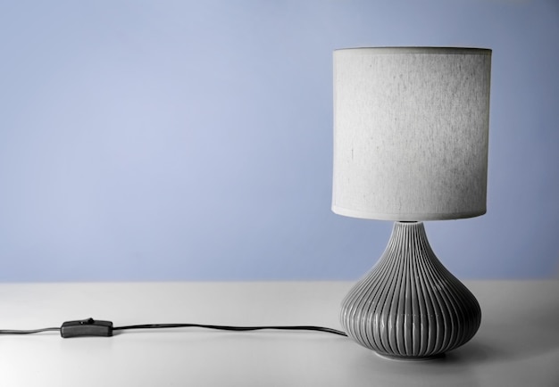 Stilvolle Lampe auf dem Tisch vor farbigem Hintergrund