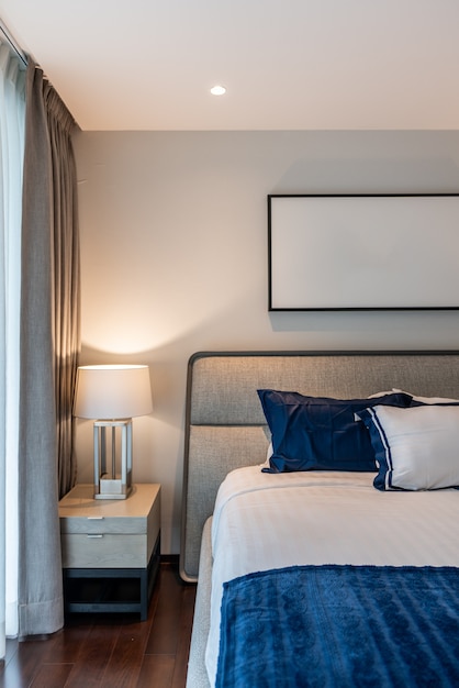 Foto stilvolle schlafzimmerecke mit grauem stoffkopfteil und bett mit weichen kisseneinstellung mit dunkelblau-weiß gestrichener wand im hintergrund / gemütliches innendesign / modernes interieur