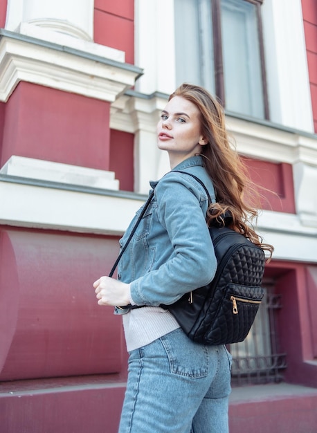 Stilvolle sexy Frau in Jeanskleidung und Rucksack in der Stadt