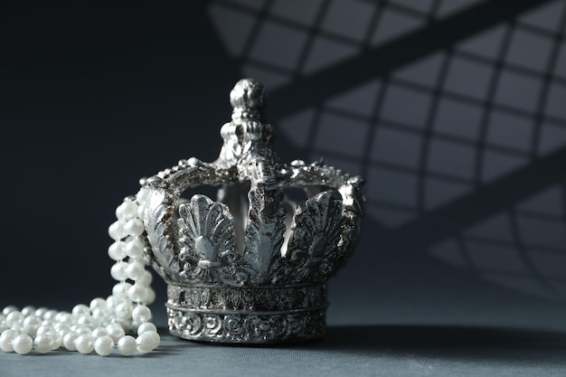 Stilvolle silberne Krone und elegante Perlenschmuck vor grauem Hintergrund