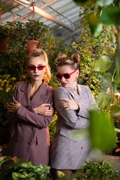 Stilvolle Sonnenbrille. Schöne attraktive Frauen, die mit gekreuzten Händen stehen und schöne Accessoires tragen