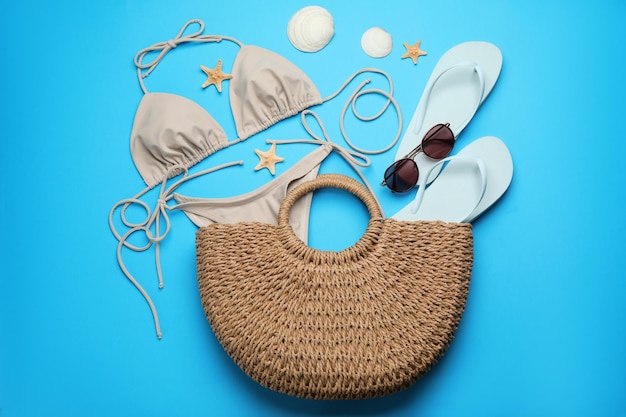 Stilvolle Tasche mit Strandzubehör auf hellblauem Hintergrund flach gelegt