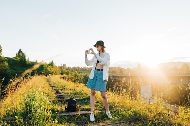 Stilvolle Touristin mit Hut und Sonnenbrille in Sommerkleidung steht auf einem alten Viadukt