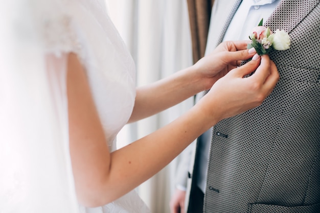 Stilvolle Trauzeugen, die dem glücklichen Bräutigam helfen, sich am Morgen für die Hochzeitszeremonie fertig zu machen. Luxusmann im Anzug im Zimmer. Hochzeitstag.