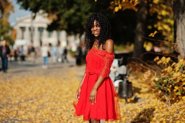 Stilvolle, trendige, lockige Afro-Frankreich-Frau posierte am Herbsttag in rotem Kleid Schwarzafrikanisches weibliches Modell