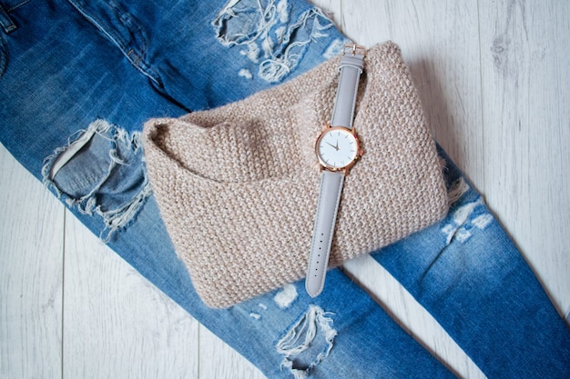 Stilvolle Uhr auf einem Pullover und zerrissenen Jeans