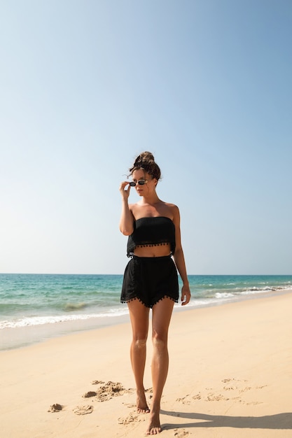 Stilvolle und schöne Frau, die am Strand aufwirft