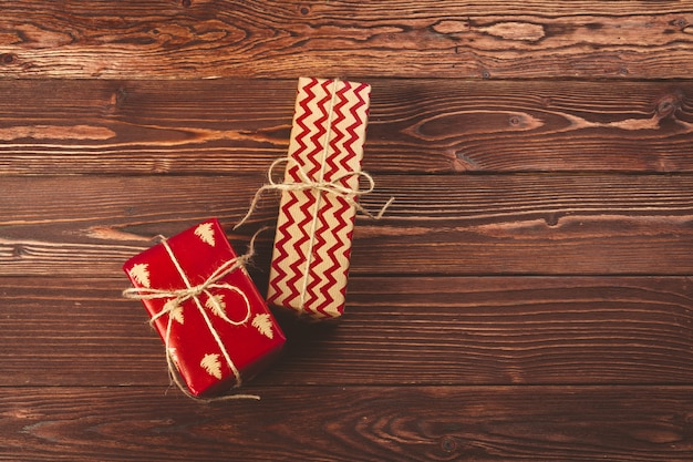 Stilvolle verzierte Weihnachtsgeschenke über braunem hölzernem Hintergrund
