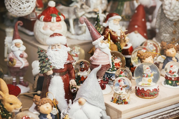 Stilvolle Weihnachts-Souvenirs Weihnachtsmänner Schneekugeln Schneemann Spielzeug in der Vitrine des festlichen Ladens Modernes Weihnachtsdekor in der Stadtstraße Winterferien in Europa Frohe Weihnachten
