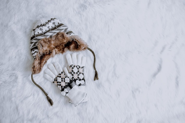 Stilvolle Winterhandschuhe und Hut auf pelzweißem Hintergrund.