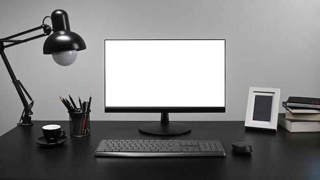 Stilvoller Arbeitsplatz mit Computer-PC-Bilderrahmen, Kaffeetasse, Stifthalter und Lampe