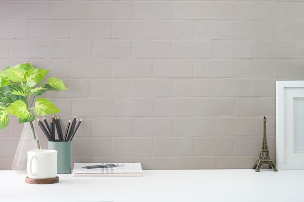 Stilvoller Arbeitsplatz mit Kaffeetassen-Bleistifthalter und Topfpflanze auf weißem Tisch Kopieren Sie Platz für Ihren Text