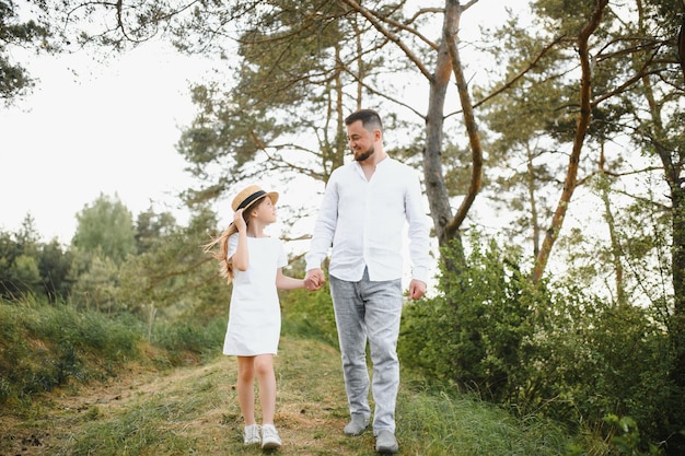 Stilvoller bärtiger Vater mit seiner kleinen Tochter geht im Sommerpark spazieren