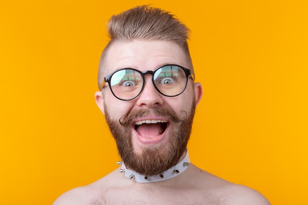 Stilvoller junger Hipster-Mann mit Schnurrbart und Bart öffnet freudig seinen Mund an einer gelben Wand. Konzept der Überraschung und Feier. Copyspace.