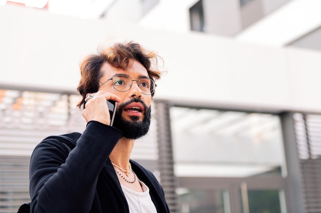 Stilvoller junger Mann, der an einem Mobiltelefon spricht