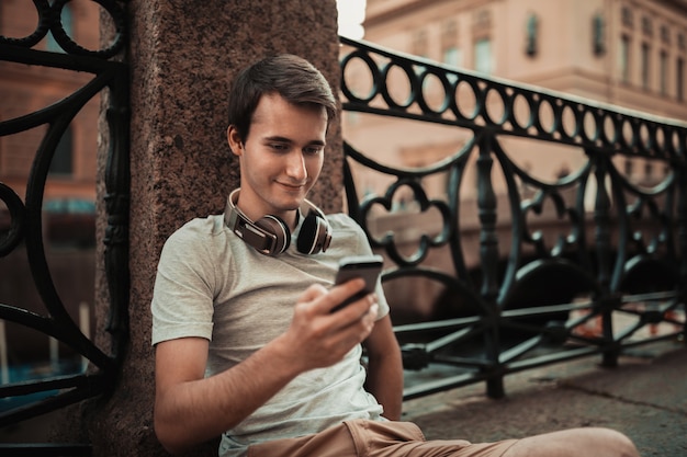 Stilvoller junger Mann, der den Handy im Freien verwendet
