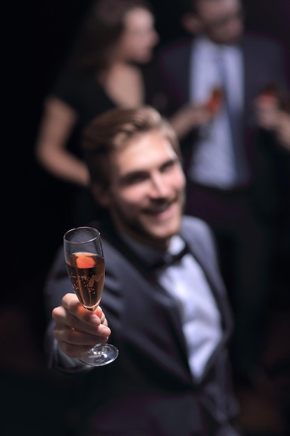 Stilvoller junger Mann, der mit einem Glas Champagner steht