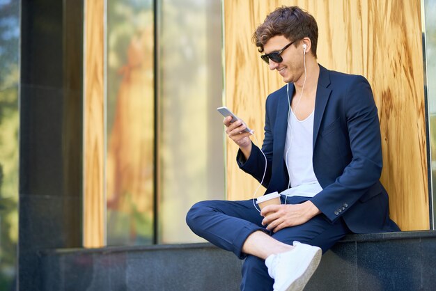 Stilvoller junger Mann mit Smartphone im Freien