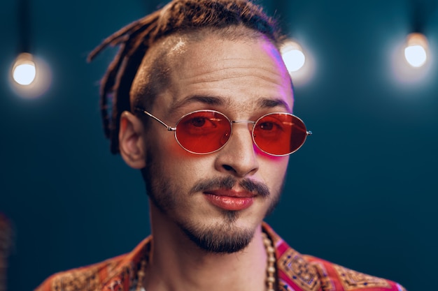 Stilvoller Kerl mit Dreadlocks, die rosa Sonnenbrille tragen