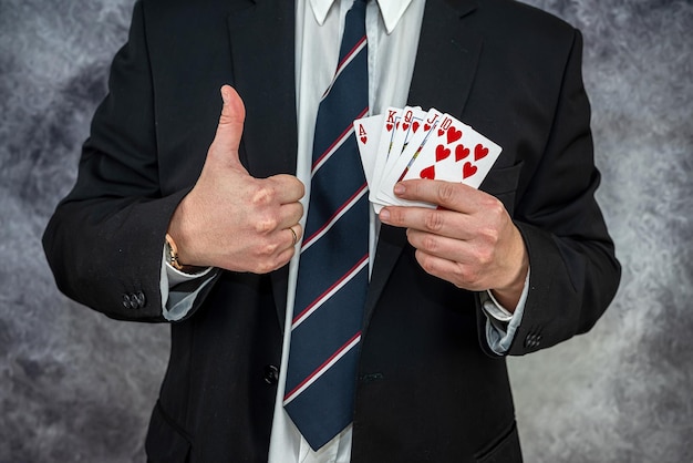 Stilvoller Mann im schwarzen Anzug mit Spielkarten und Pokerchips im Casino