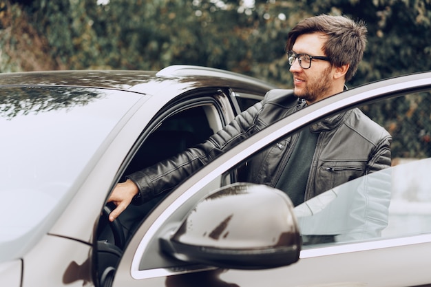 Stilvoller Mann in der Brille sitzt in einem Auto