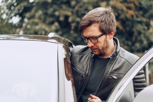 Stilvoller Mann in Gläsern sitzt in einem Auto, Nahaufnahmeporträt