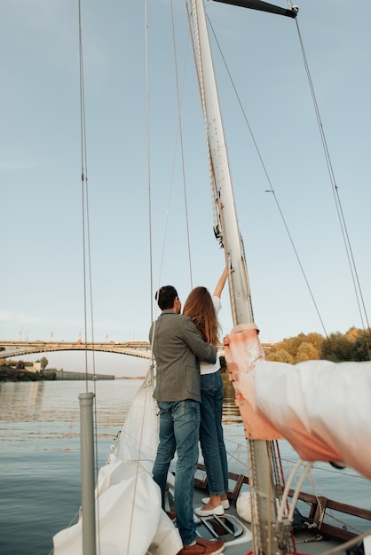 Stilvoller Mann und Frau, die sich auf einer Yacht umarmen, geht auf den Fluss