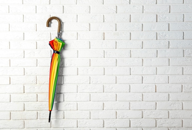 Stilvoller Regenbogenschirm, der an einer Ziegelwand hängt