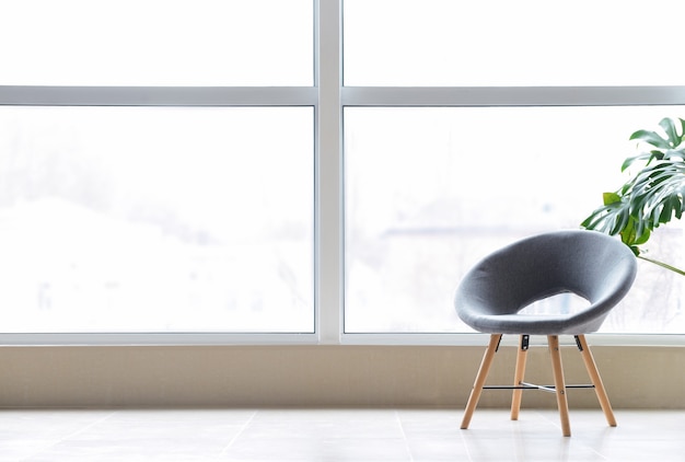 Stilvoller Stuhl in der Nähe eines großen Fensters im Zimmer