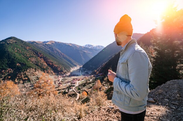 Stilvoller trendiger Hipster-Mann-Reisender in einem gelben Hut und in einer Jeansjacke steht auf den Bergen und im Uzungol-See in Trabzon während der Türkei-Reise