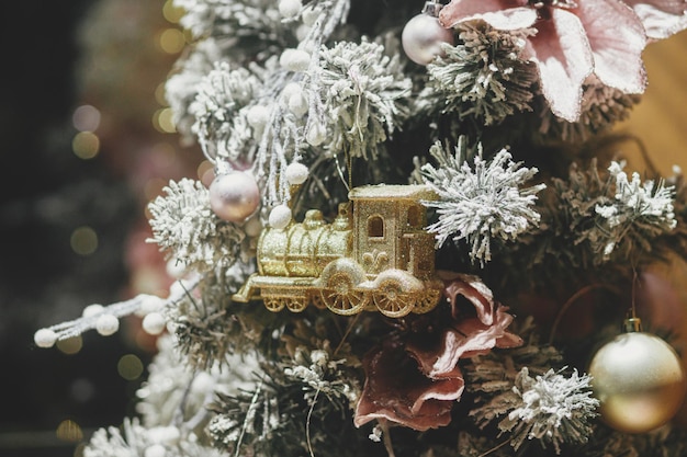 Stilvoller Weihnachtsbaum mit goldenem Zugspielzeug in Schaufenster am Abend Moderne Weihnachtsdekoration in der Stadtstraße Atmosphärische Winterferien in Europa Frohe Weihnachten und schöne Feiertage