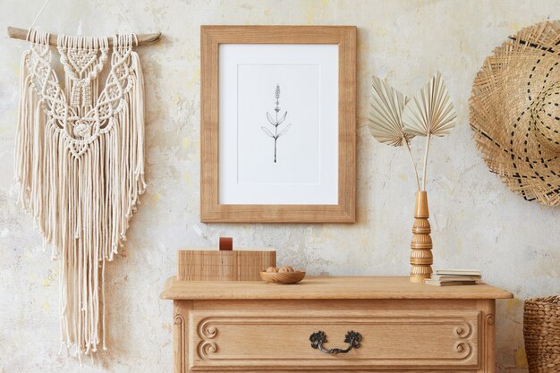 Stilvolles Boho-Interieur des Wohnzimmers mit braunem Rahmen, eleganten Accessoires, Blumen in Vase, Holzregal und hängender Rattanhütte. Minimalistisches Konzept der Wohnkultur..