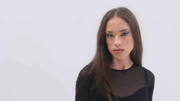 Stilvolles brünettes Mädchen mit hellem Make-up in einer schwarzen transparenten Bluse auf weißem Hintergrund