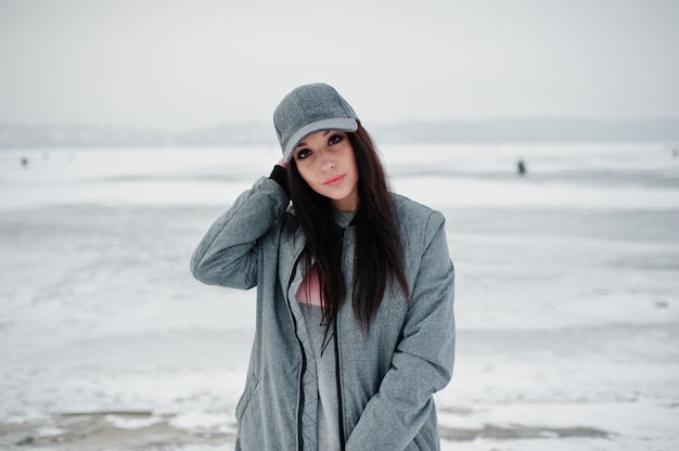 Stilvolles Brunettemädchen in der grauen Kappe am Wintertag.