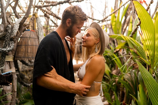 Stilvolles Coupé in Liebeshaltung im tropischen Garten Böhmische blonde Frau, die sich mit ihrem hübschen Freund umarmt