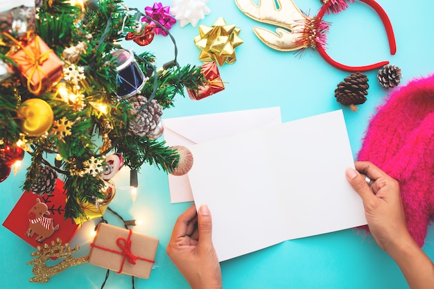 Stilvolles Ebenenlage Weihnachtskonzept, Frau, die leere Karte hält.