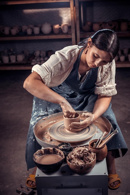 Stilvolles Handwerkermädchen demonstriert den Prozess der Herstellung von Keramikgeschirr mit der alten Technologie. Handwerkliche Produktion.