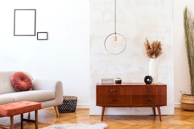 Stilvolles Interieur des Wohnzimmers mit grauem Designsofa, Möbeln, runder Pendelleuchte, eleganten Accessoires und Fotorahmen in minimalistischer Wohnkultur.