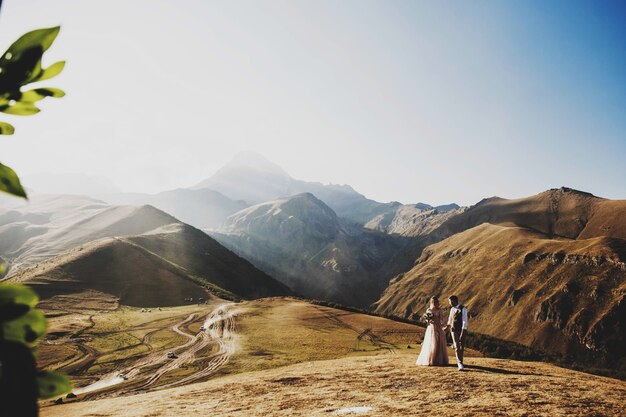 Stilvolles junges Hochzeitspaar hat den Spaß, der in den schönen georgischen Bergen aufwirft