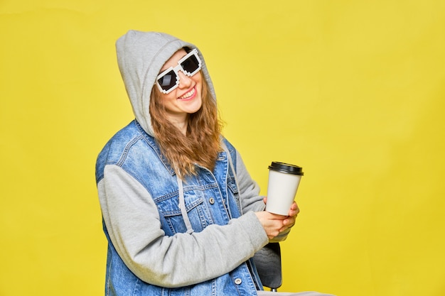 Stilvolles kaukasisches Mädchen in Jeans und Brille auf Gelb