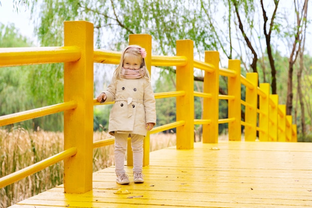 Stilvolles kleines Mädchen auf einer gelben Brücke im Park