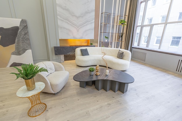 Stilvolles, luxuriöses Interieur eines modernen Studio-Apartments in grünen Pastellfarben mit Holzelementen, teuren Möbeln und Dekorationen, gemütliche Sitzecke neben dem Kamin